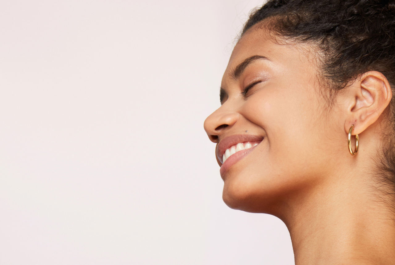 woman smiling, eyes closed on pink background